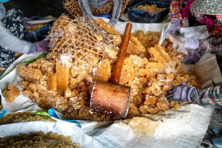 Artisanal sugar being processed with wooden tools in a vibrant market setting.